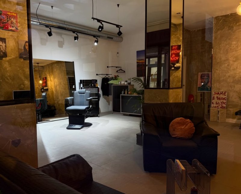 Interior de la barbería con sillón de barbero, paredes de estuco dorado y focos